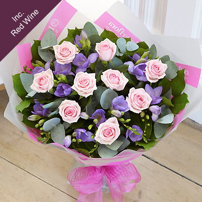 Delicate Freesia, 14 large-headed Roses and choice foliage are tied together to create this beautifu