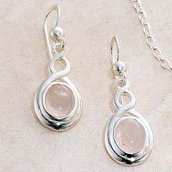 Gently curving lines in sterling silver encircle a delicate stone of rose quartz